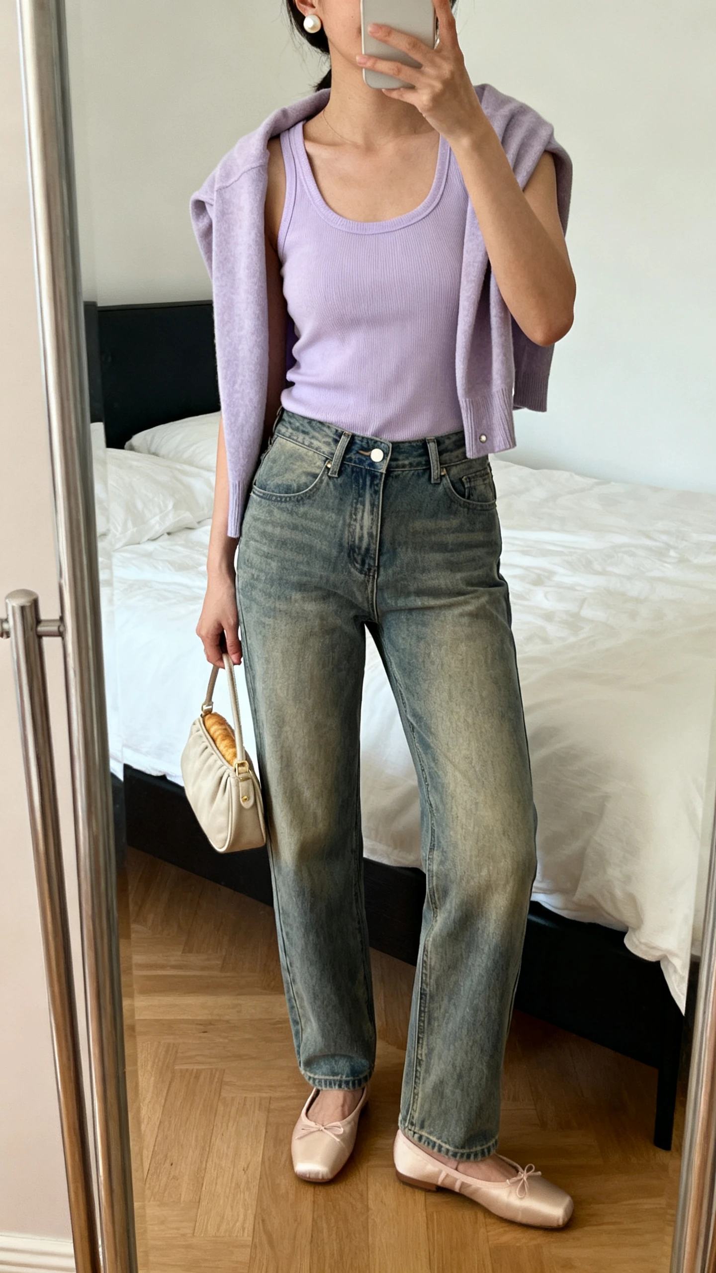 iPhone mirror selfie of a woman in a pastel lavender tank, vintage-wash straight-leg jeans, leather ballet flats, a cropped cardigan draped over shoulders, a small baguette bag, and pearl studs; face not visible, cropped at shoulders, bedroom mirror, soft morning light, iPhone photo quality.